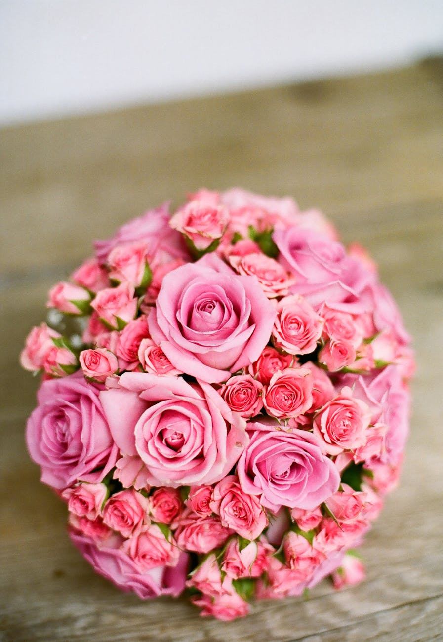 Beautiful circular arrangement of pink roses displayed on a rustic wooden surface.