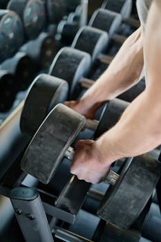 A focused man lifts heavy weights on a bench press machine in a dimly lit gym.